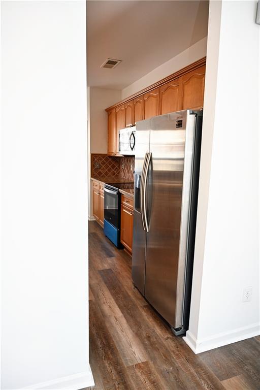 kitchen with stainless steel fridge, decorative light fixtures, a chandelier, and dark wood-type flooring