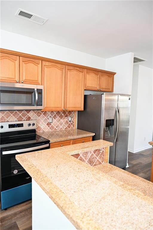 kitchen featuring appliances with stainless steel finishes, backsplash, and dark hardwood / wood-style flooring