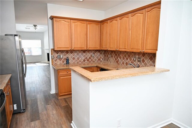 kitchen featuring tasteful backsplash, hardwood / wood-style floors, light stone counters, and appliances with stainless steel finishes