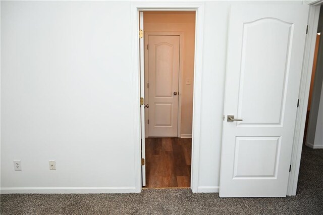 unfurnished bedroom with a walk in closet, dark carpet, and a closet