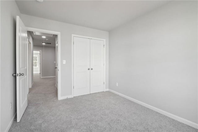 unfurnished bedroom featuring light colored carpet and a closet