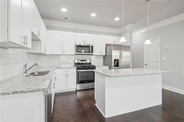 kitchen featuring appliances with stainless steel finishes, decorative light fixtures, white cabinetry, sink, and a center island