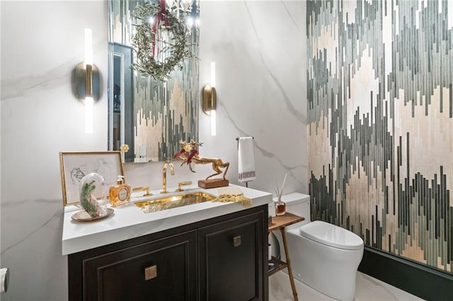 bathroom featuring vanity, tile walls, and toilet