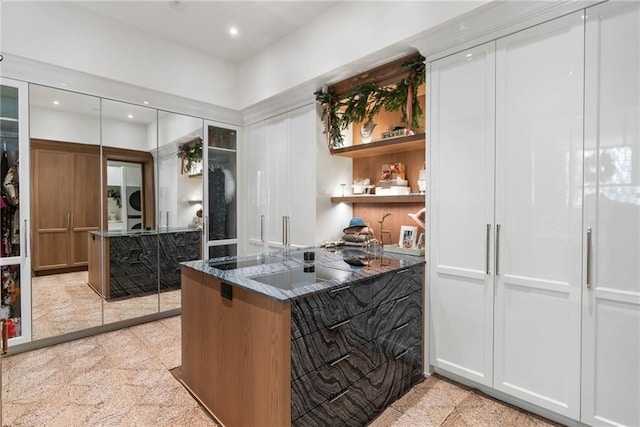 kitchen featuring dark stone countertops, kitchen peninsula, and white cabinets