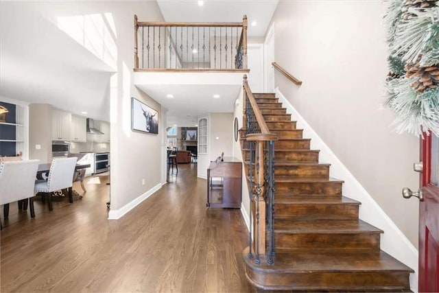 staircase featuring a high ceiling and wood-type flooring