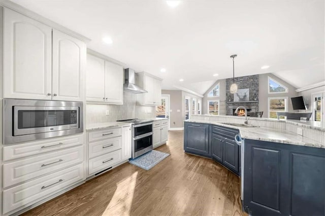 kitchen with sink, appliances with stainless steel finishes, white cabinets, and wall chimney exhaust hood