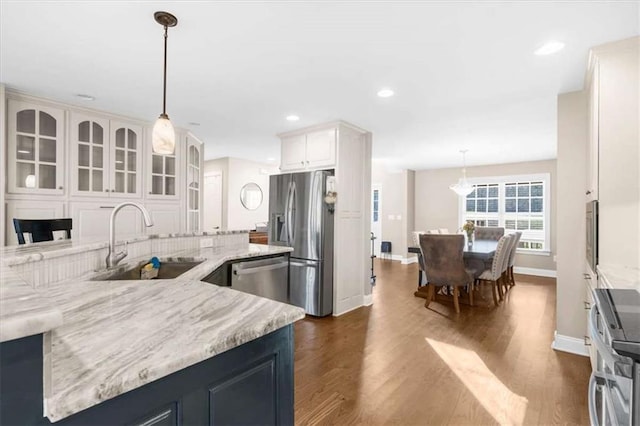 kitchen featuring stainless steel appliances, sink, dark hardwood / wood-style flooring, and decorative light fixtures