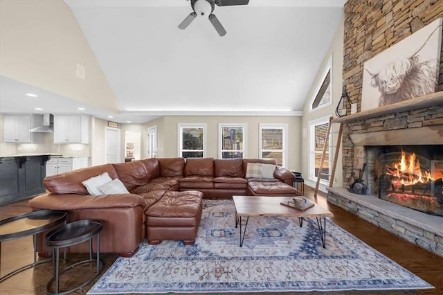 living room featuring ceiling fan, high vaulted ceiling, a stone fireplace, and dark hardwood / wood-style floors