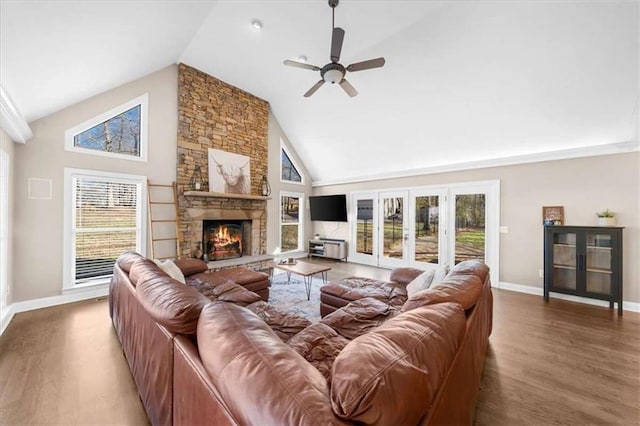 living room with ceiling fan, high vaulted ceiling, a stone fireplace, and wood-type flooring