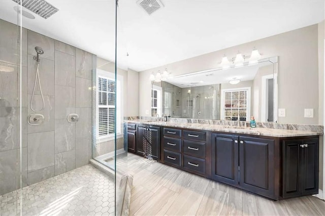 bathroom with a tile shower and vanity