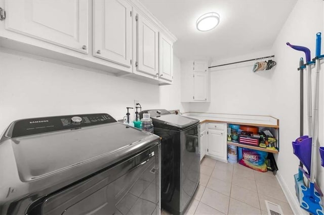 clothes washing area with light tile patterned floors, separate washer and dryer, and cabinets