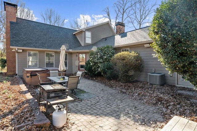 rear view of property featuring a hot tub, a patio, and central air condition unit