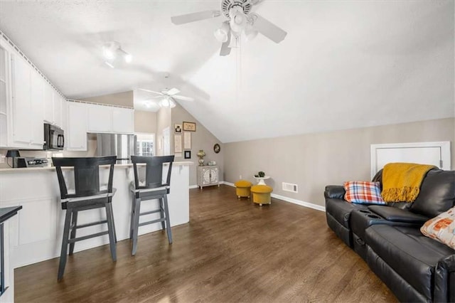 living room with dark wood-type flooring, vaulted ceiling, and ceiling fan