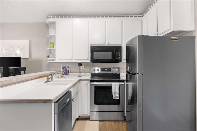 kitchen featuring appliances with stainless steel finishes, sink, light wood-type flooring, kitchen peninsula, and white cabinets