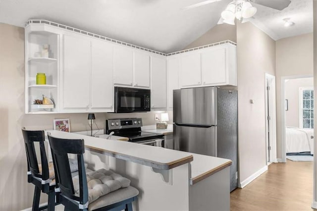 kitchen with kitchen peninsula, appliances with stainless steel finishes, white cabinets, and a kitchen bar