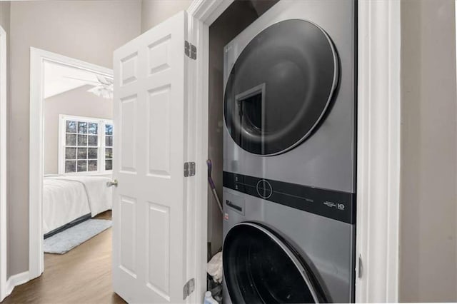 laundry room featuring hardwood / wood-style floors and stacked washer / dryer