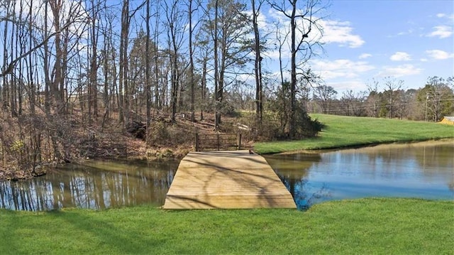 dock area with a lawn and a water view