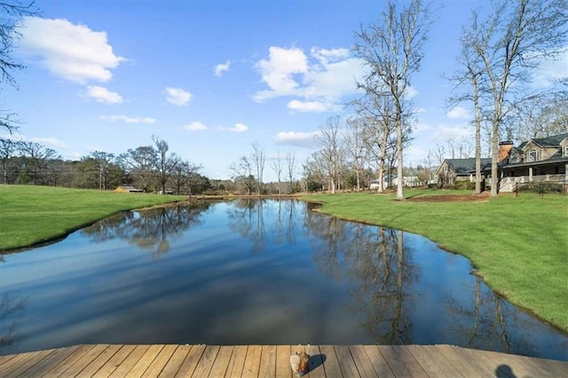 view of dock with a yard and a water view