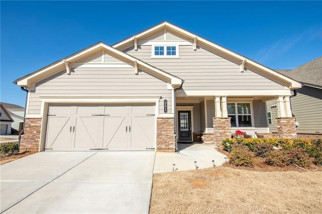 craftsman-style home with a garage, concrete driveway, and stone siding