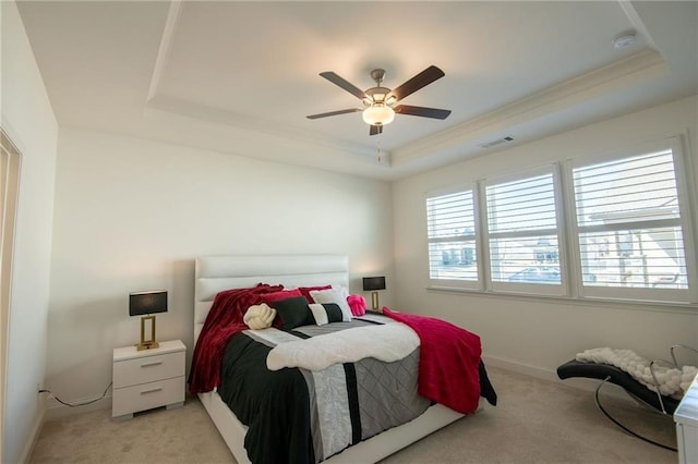 bedroom with baseboards, a tray ceiling, multiple windows, and light colored carpet