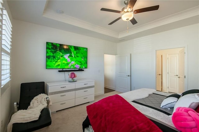 bedroom with light carpet, a ceiling fan, a tray ceiling, and crown molding