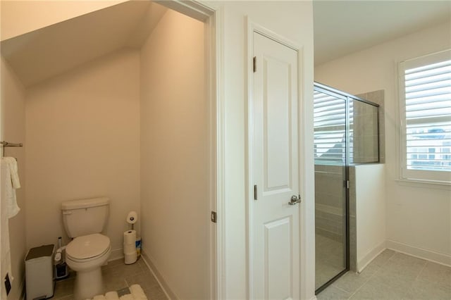 bathroom featuring toilet, a stall shower, tile patterned flooring, and baseboards