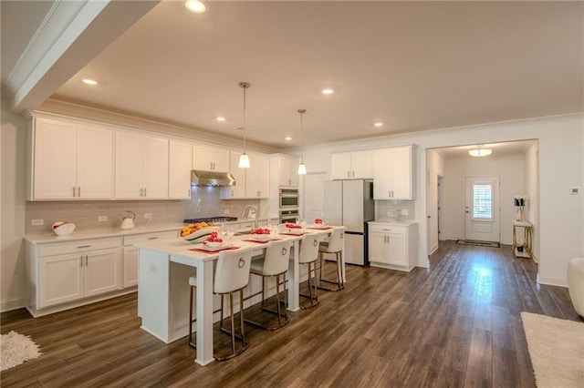 kitchen featuring stainless steel appliances, white cabinets, and under cabinet range hood