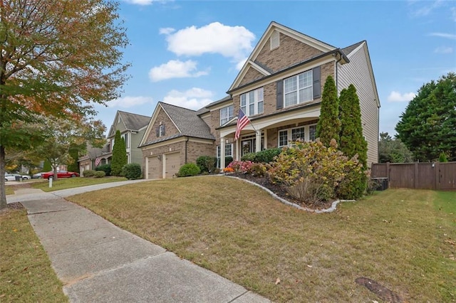 craftsman house with driveway, fence, a front lawn, and brick siding