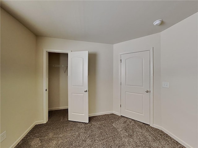 unfurnished bedroom featuring a closet and dark colored carpet