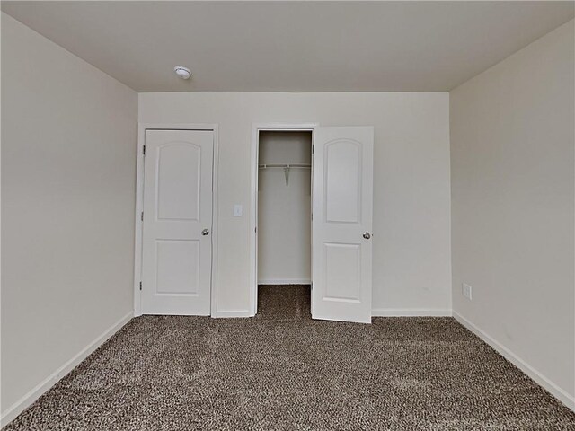 unfurnished bedroom featuring a closet and dark carpet