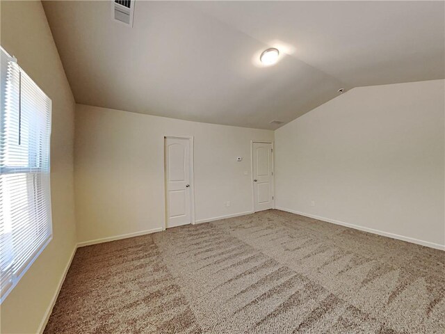 spare room with carpet and vaulted ceiling