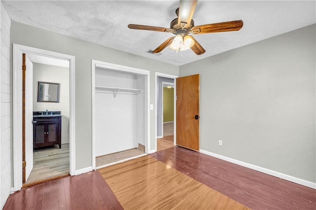 unfurnished bedroom featuring ceiling fan, hardwood / wood-style floors, a closet, and a textured ceiling