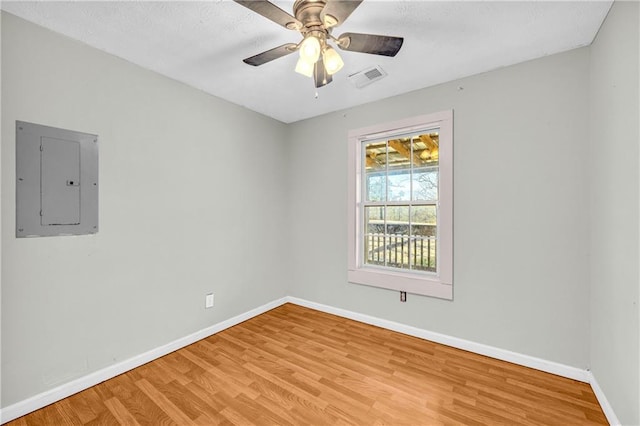 empty room featuring electric panel, light hardwood / wood-style floors, and ceiling fan