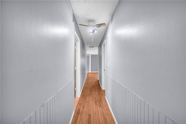 corridor with light hardwood / wood-style floors and a textured ceiling