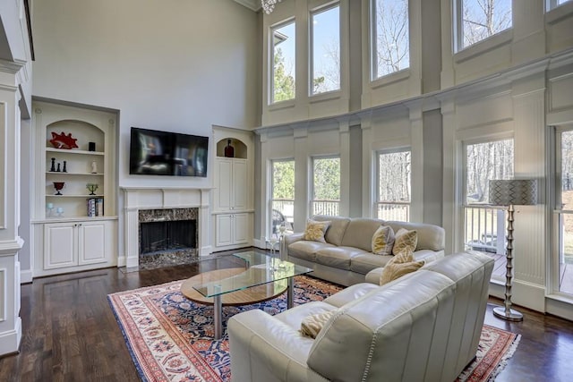 living room featuring a high end fireplace, dark wood-style floors, and a wealth of natural light