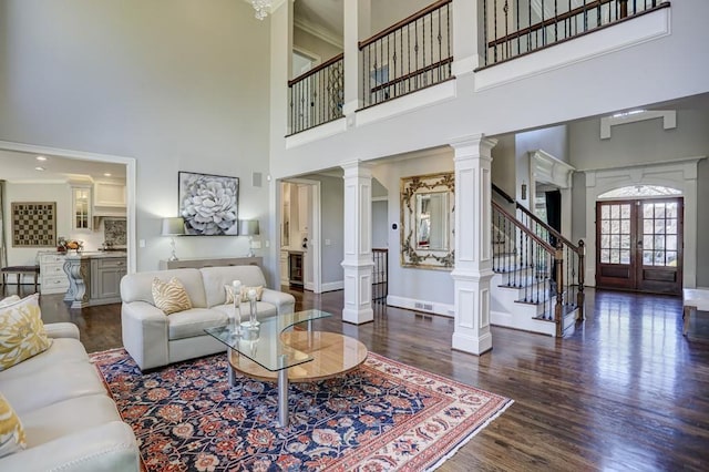 living room featuring french doors, wood finished floors, stairs, and ornate columns