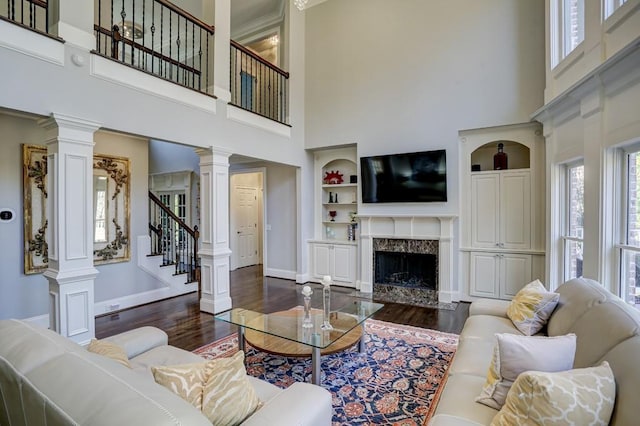 living room with built in features, decorative columns, dark wood finished floors, and a fireplace