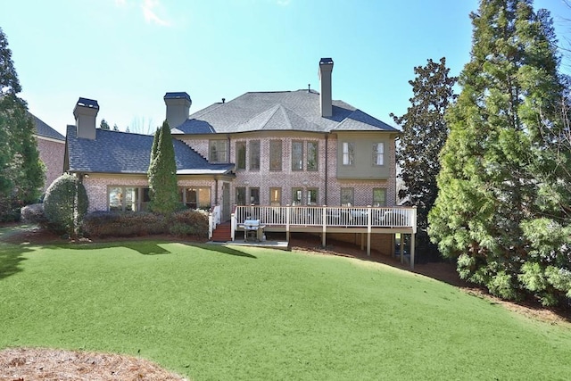 back of property featuring a wooden deck, a lawn, a chimney, and brick siding