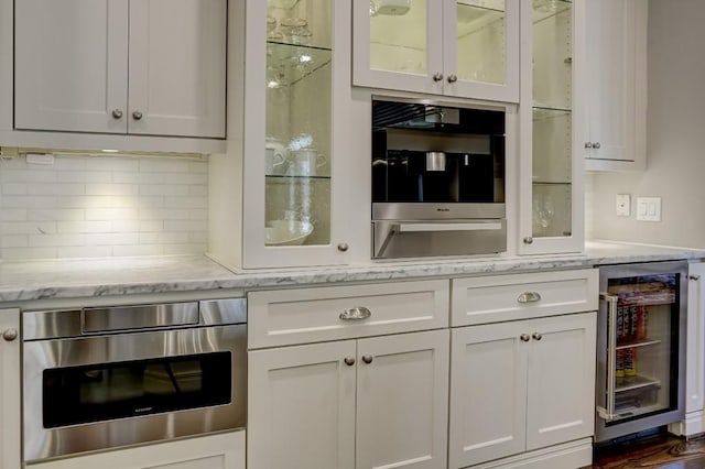 kitchen featuring white cabinetry, glass insert cabinets, beverage cooler, and tasteful backsplash