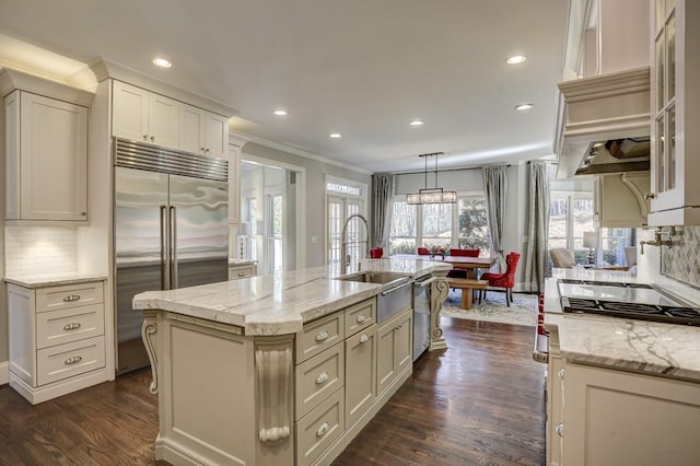 kitchen with dark wood-type flooring, an island with sink, a sink, tasteful backsplash, and stainless steel appliances