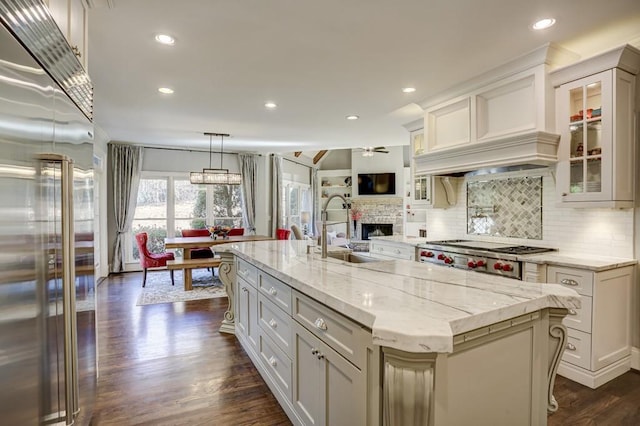 kitchen featuring light stone counters, stainless steel appliances, a ceiling fan, and a sink