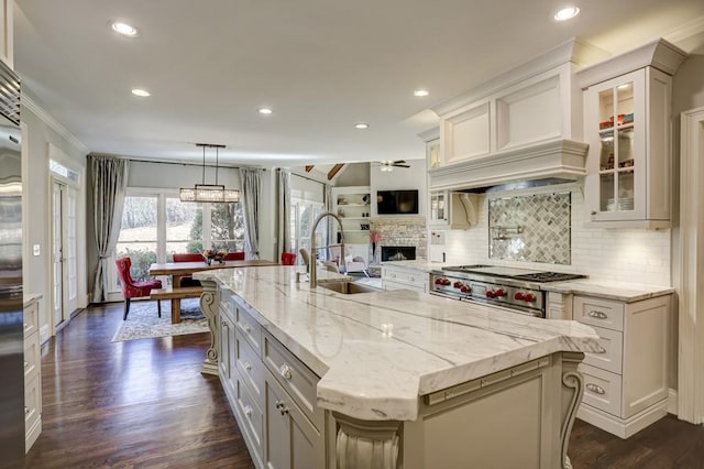 kitchen with a sink, cooktop, light stone counters, and a fireplace