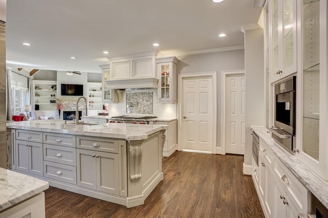 kitchen featuring dark wood finished floors, open floor plan, a center island with sink, stainless steel gas cooktop, and a sink