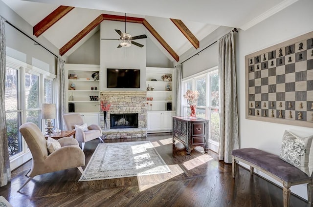 living area featuring plenty of natural light, built in features, a stone fireplace, and wood finished floors