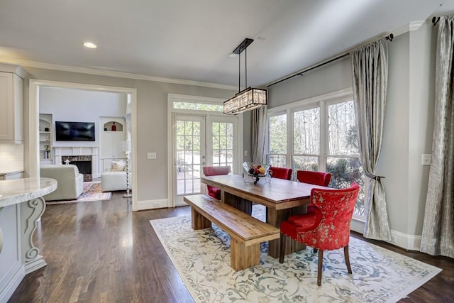 dining space with a high end fireplace, crown molding, dark wood-style floors, and a wealth of natural light