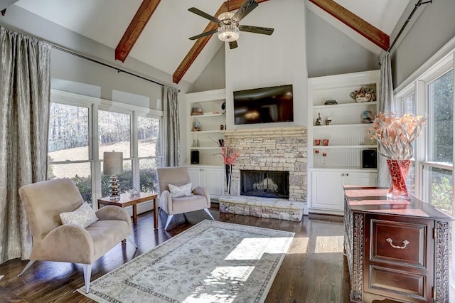 living area with beamed ceiling, high vaulted ceiling, built in features, dark wood finished floors, and a stone fireplace