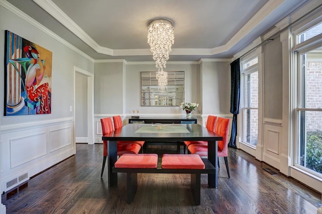 dining space featuring visible vents, a wainscoted wall, dark wood-type flooring, a raised ceiling, and a chandelier