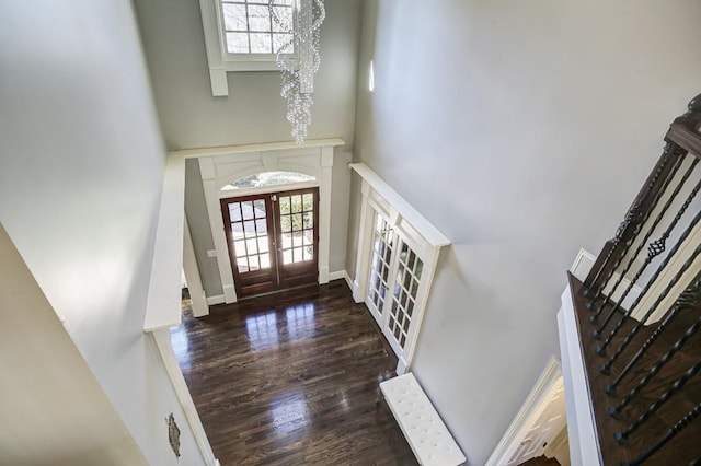 entrance foyer with french doors, wood finished floors, a towering ceiling, and a chandelier