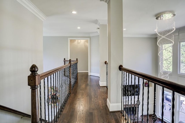 hall with wood finished floors, an upstairs landing, baseboards, and ornamental molding