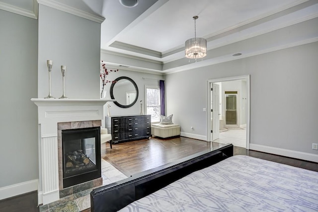 bedroom with baseboards, a raised ceiling, and crown molding